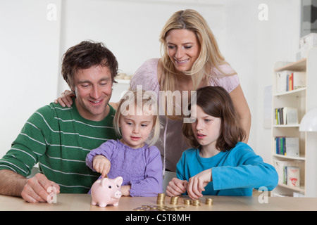 Deutschland, Bayern, München, Familie mit Münzen und Sparschwein, Lächeln Stockfoto