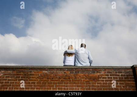 Deutschland, Bayern, München, junges Paar sitzt oben auf der Mauer Stockfoto