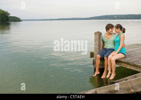 Deutschland, Bayern, Starnberger See, junges Paar sitzt am Steg Stockfoto