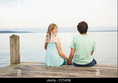 Deutschland, Bayern, Starnberger See, junges Paar sitzt am Steg, Rückansicht Stockfoto