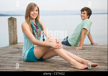 Deutschland, Bayern, Starnberger See, junges Paar sitzt am Steg Stockfoto