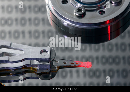 Festplatte des Computers geöffnet, schreiben/lesen Kopf und Festplatte. Binär-Code Zahlen spiegeln sich auf der Festplatte. Symbol. Stockfoto