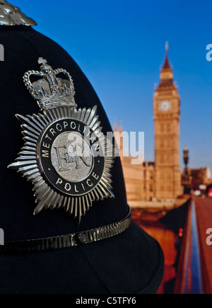 Polizeihelm und Dienstmarke mit Houses of Parliament und der Themse dahinter. Konzept Police Law Politics Westminster London UK Stockfoto