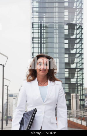 Deutschland, Köln, Geschäftsfrau mit Laptop neben Rhein River und Kran-Haus im Hintergrund, Lächeln, Porträt Stockfoto