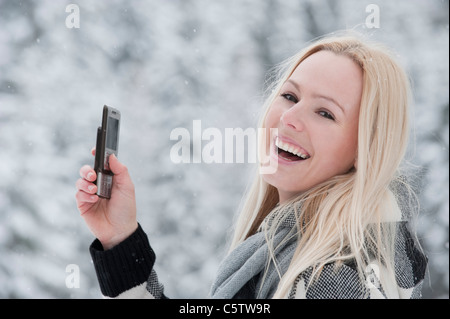 Österreich, Salzburger Land, Altenmarkt, Zauchensee, junge Frau mit Handy, lachen, portrait Stockfoto