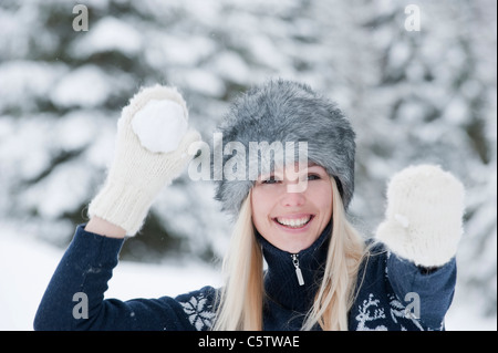 Österreich, Salzburger Land, Altenmarkt, Zauchensee, junge Frau werfen Schneeball, Lächeln, Porträt, Nahaufnahme Stockfoto