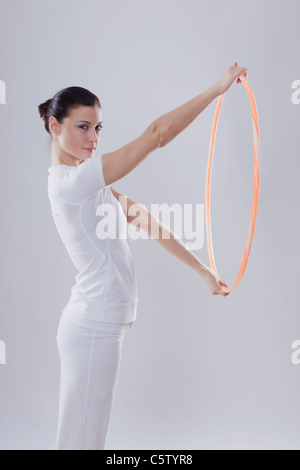 Mitte Erwachsene Frau mit Hoola Hoop vor weißem Hintergrund, Lächeln, Porträt Stockfoto