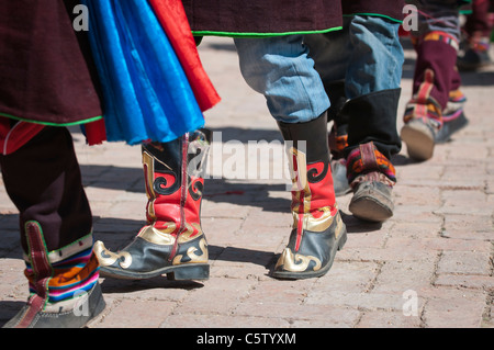 Tänzer tragen verzierte Stiefel bei Schamanen Erntefest, Tongren, Qinghai Provinz, China Stockfoto