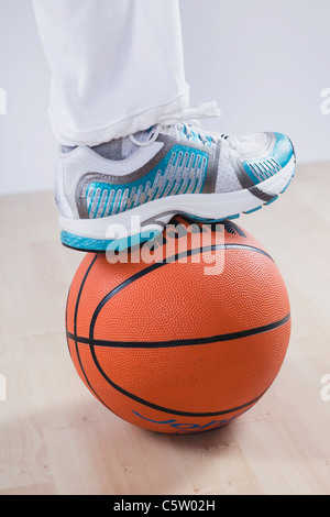 Nahaufnahme eines Bein auf Basketball vor weißem Hintergrund Stockfoto