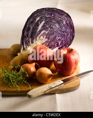 Rotkohl, Äpfel, Kartoffeln, Thymian und Zwiebeln auf Schneidebrett Stockfoto