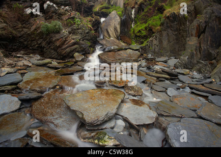Kleiner Wasserfall fließt nach unten über Schiefer an der Combesgate Bucht-Strand an der Küste von Nord-Devon, UK Stockfoto