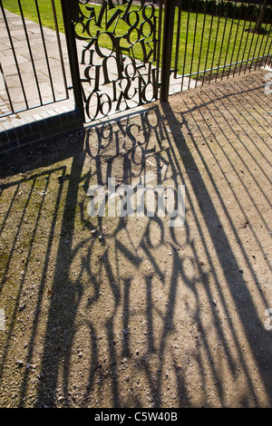 Durcheinander von Buchstaben in einem schmiedeeisernen Tor mit Schatten auf den Boden durch starke Sonneneinstrahlung Stockfoto