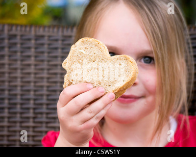 Deutschland, Bayern, Nahaufnahme von Mädchen halten Brotscheibe, Lächeln, Porträt Stockfoto