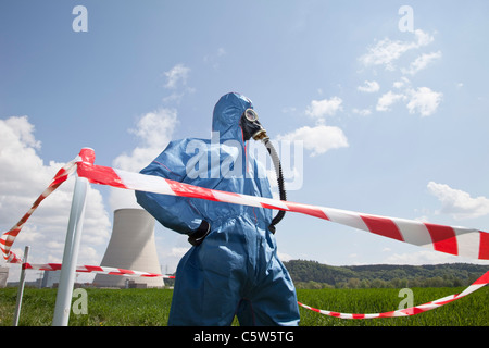 Deutschland, Bayern, Unterahrain, Mann mit Schutzkleidung im Feld am AKW Isar und Cordon Tape im Vordergrund stehen Stockfoto