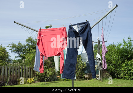 Nasse Haushaltskleidung, die an einer Drehwaschleitung hängt, um an einem warmen sonnigen Tag im Freien in einem Garten zu trocknen. England, Großbritannien, Großbritannien. Stockfoto