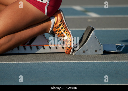 Teenager-Mädchen in Startlöchern auf einer Laufstrecke von blau- und Grautönen Stockfoto