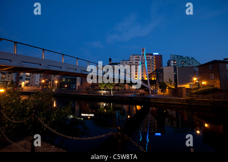 Eine Fußgängerbrücke über die Leeds und Liverpool Canal in Leeds City Centre in der Abenddämmerung Stockfoto