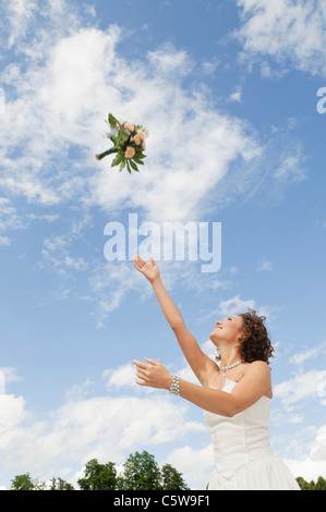 Deutschland, Bayern, junge Braut wirft einen Blumenstrauß in den Himmel Stockfoto