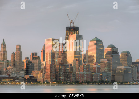 Der Sonnenaufgang Himmel gefärbt wird von Gebäuden in lower Manhattan, darunter World Financial Center und Battery Park City reflektiert. Stockfoto