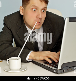 Lustige Geschäftsmann heißen Kaffee zu trinken und arbeiten im Internet Stockfoto