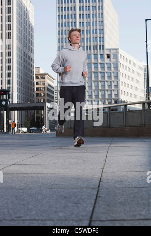 Deutschland, Berlin, junger Mann Joggen, Hochhäuser im Hintergrund Stockfoto