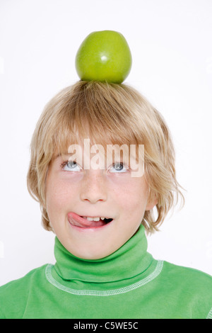 Kleiner Junge (10-11) ausgleichende Apfel auf Kopf Stockfoto