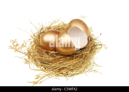 Zwei ganze und einem gebrochenen goldenen Eiern in einem Stroh nest Stockfoto