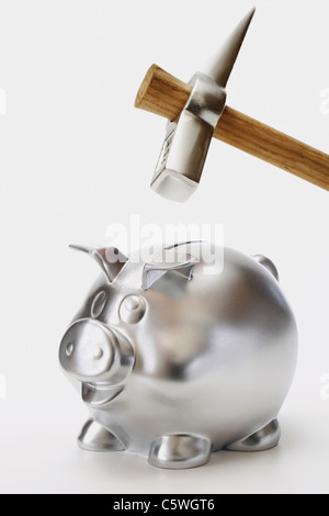 Silber-Sparschwein mit Hammer drauf vor weißem Hintergrund, Nahaufnahme Stockfoto