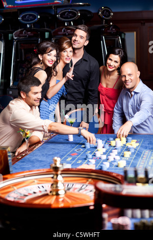 Junge, glückliche Menschen, die das Casino Roulette spielen Stockfoto