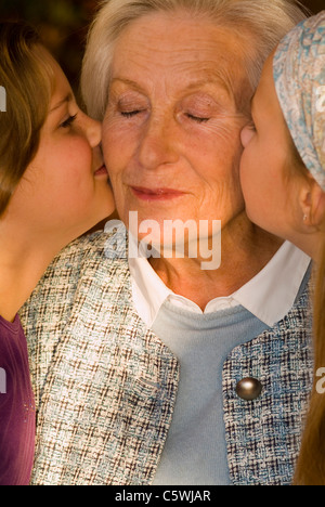 Zwei Mädchen (8-11) küssen Großmutter, close-up Stockfoto