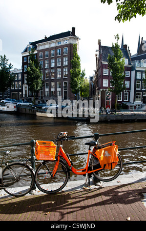 Orange Fahrrad angekettet an der Brücke über Singel Gracht in Amsterdam. Orange ist die Farbe der königlichen Familie in den Niederlanden. Stockfoto