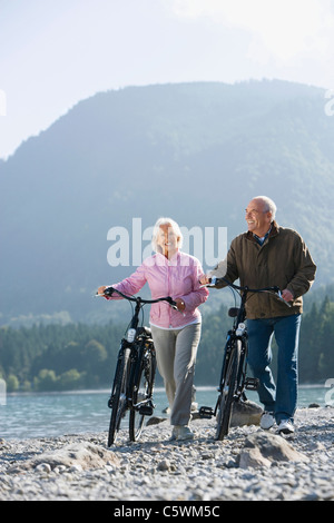 Deutschland, Bayern, Walchensee, Senior paar schieben die Räder über Seeufer Stockfoto