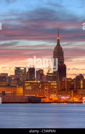 Der Himmel beginnt zu erleichtern und die Wolken spiegeln vor Sonnenaufgang Farbe über das Empire State Building und andere Gebäude der Midtown Manhattan Skyline. Stockfoto
