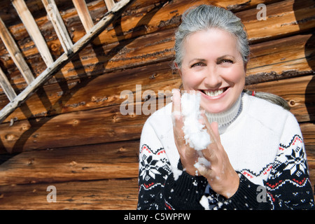 Italien, Südtirol, Seiseralm, Senior Frau mit Schnee in Händen, Lächeln, Porträt Stockfoto