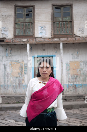 Eine junge indigenen Quechua-Frau steht vor einem sich verschlechternden Haus in Guamote, Ecuador. Stockfoto