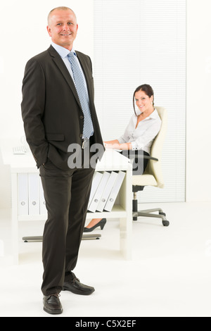 Professionelle senior Reifen Geschäftsmann, stehend im Büro mit attraktiven Sekretärin Stockfoto