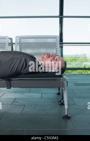 Deutschland, Leipzig-Halle, Geschäftsmann in Abflughalle Flughafen, schlafen auf Bank Stockfoto