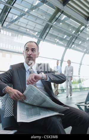 Deutschland, Leipzig-Halle, Flughafen, Geschäftsmann mit Zeitung, Geschäftsleute im Hintergrund Stockfoto