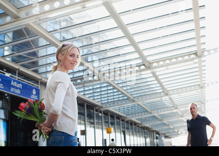 Deutschland, Leipzig-Halle, Flughafen, Frau mit Blumen, Mann im Hintergrund Stockfoto