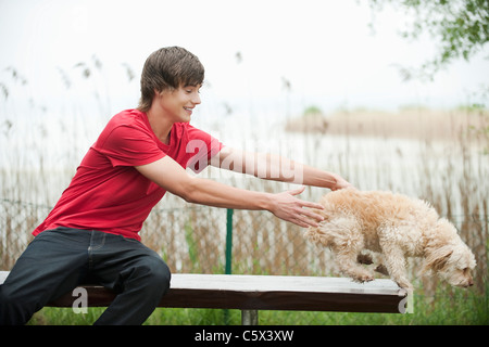 Deutschland, Bayern, Ammersee, junger Mann und Hund auf Bank, Porträt Stockfoto