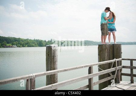 Deutschland, Bayern, Ammersee, junges Paar, die auf hölzernen Pfosten stehend Stockfoto