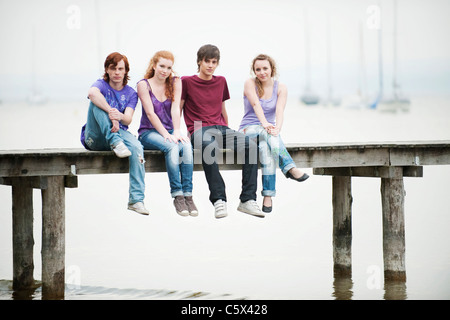 Deutschland, Bayern, Ammersee, vier Freunde sitzen auf Steg Stockfoto