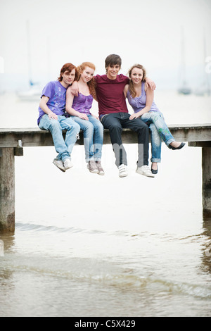 Deutschland, Bayern, Ammersee, vier Freunde sitzen auf Steg Stockfoto