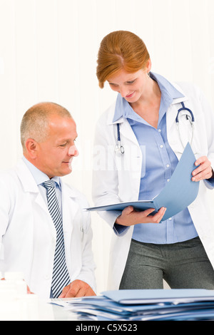 Leitender Arzt männliche mit jungen Kollegin suchen Ordner Stockfoto