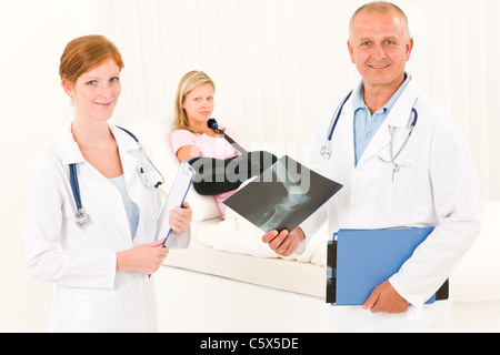 Ärztinnen und Ärzte betrachten Röntgen Krankenhauspatienten im Bett gebrochenen arm Stockfoto