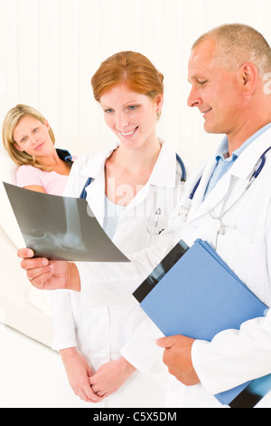 Ärztinnen und Ärzte betrachten Röntgen Krankenhauspatienten im Bett gebrochenen arm Stockfoto