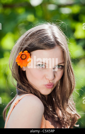 Deutschland, Bayern, Frau mit Blume im Haar, schmollend, Lippen, Porträt, Nahaufnahme Stockfoto