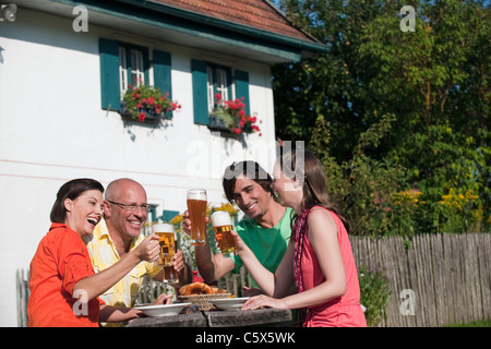 Deutschland, Bayern, vier Personen trinken Bier im Garten, Spaß, Porträt Stockfoto