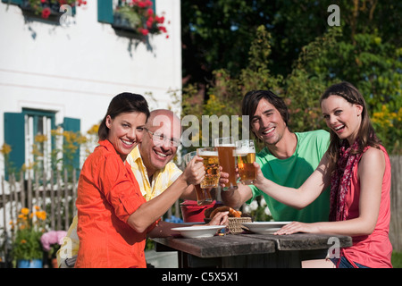 Deutschland, Bayern, Freunde trinken Bier im Garten, Gläser klirren Stockfoto