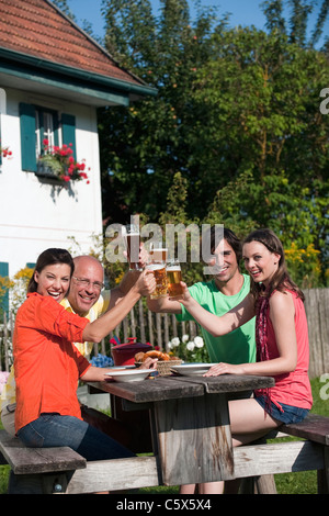 Deutschland, Bayern, Freunde trinken Bier im Garten, Gläser klirren Stockfoto